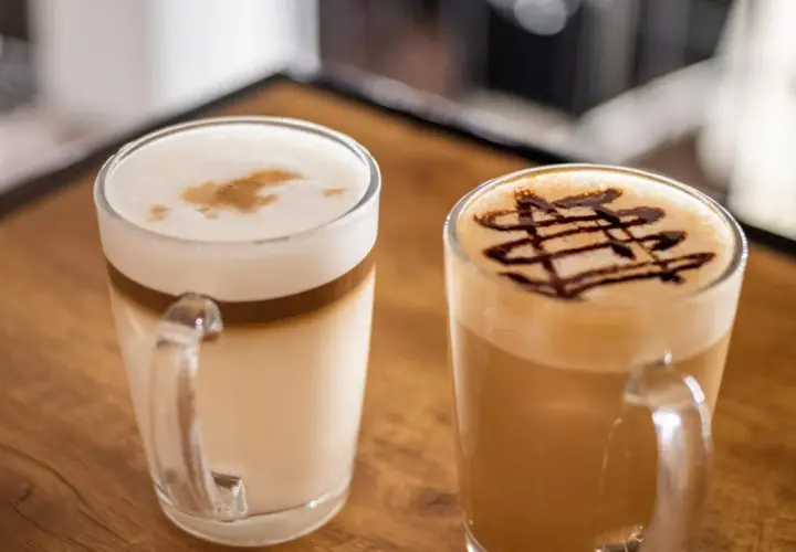 Due caffè in tazza: un macchiato vs latte con schiuma e decorazione al cioccolato.