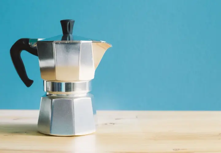 Moka italiana in alluminio, con manico nero, pronta per preparare un caffè. I suoi componenti sono ben visibili.