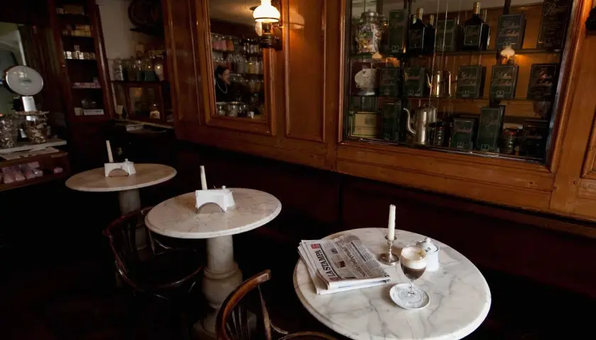 Un tavolino in marmo con un caffè, giornale e candela, in un antico caffè torinese.