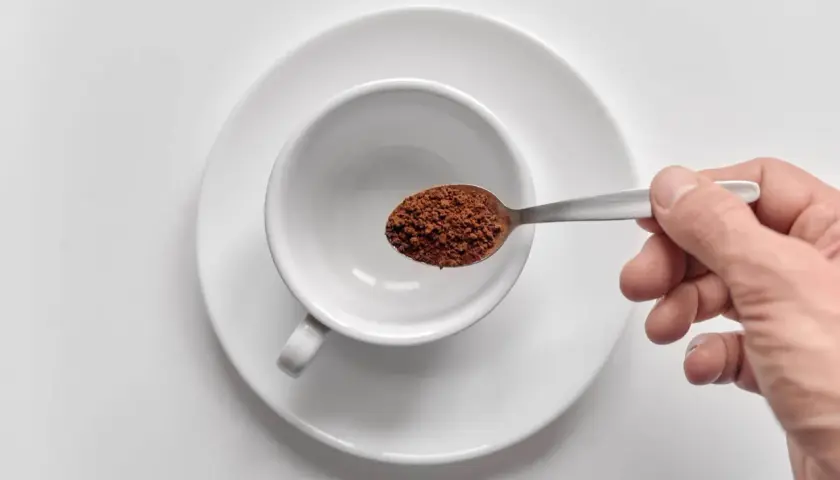 Mano che versa orzo café in una tazzina bianca.