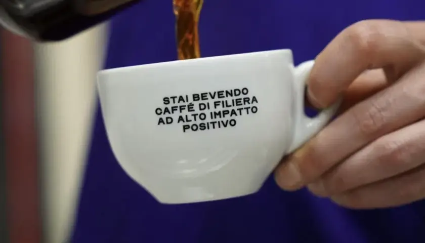 Tazza bianca con scritta "Stai bevendo caffè di filiera ad alto impatto positivo". Un caffè speciale che fa bene.