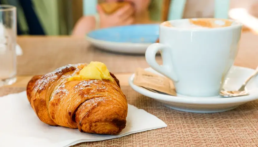 Un cornetto con crema e una tazza di cappuccino, un classico per la colazione italiana a casa.
