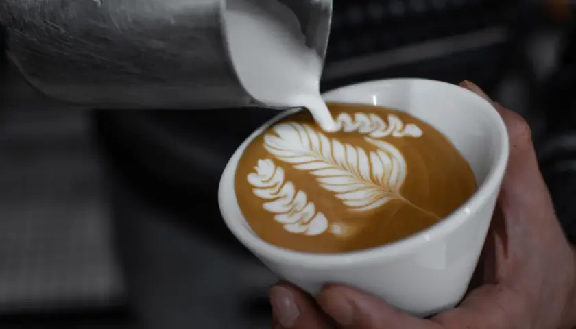 Chiara Bergonzi crea un capolavoro di latte art, versando schiuma cremosa su un caffè per formare un disegno a foglia.