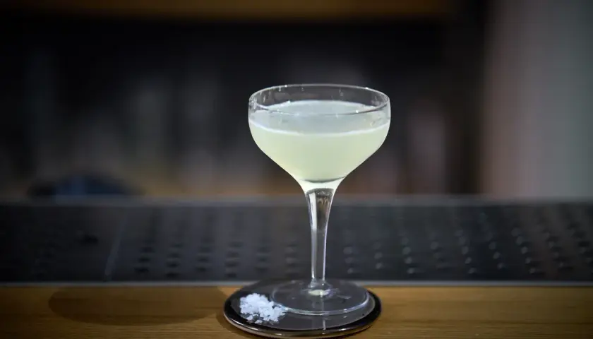Un bicchiere di cocktail aspri, con sale grosso sul piattino, pronto per essere gustato.