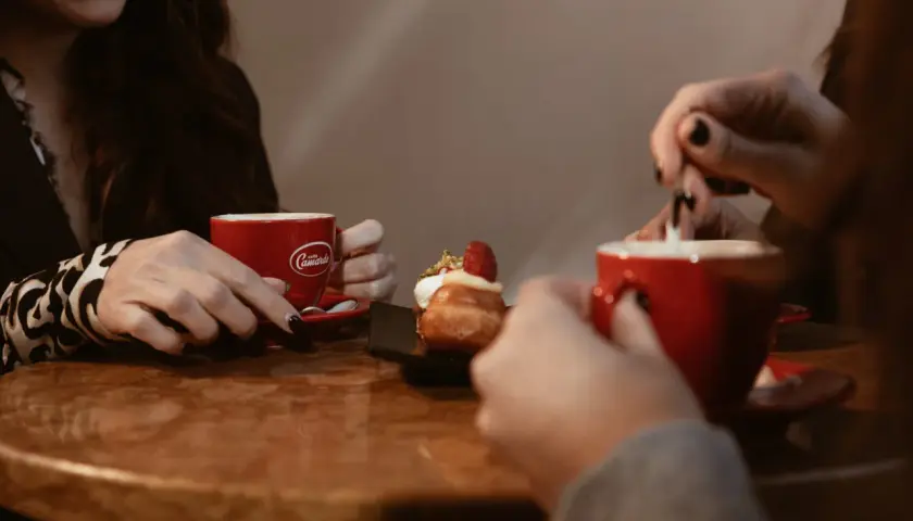 Due donne gustano un delizioso caffè e un dolce, condividendo un momento di relax.