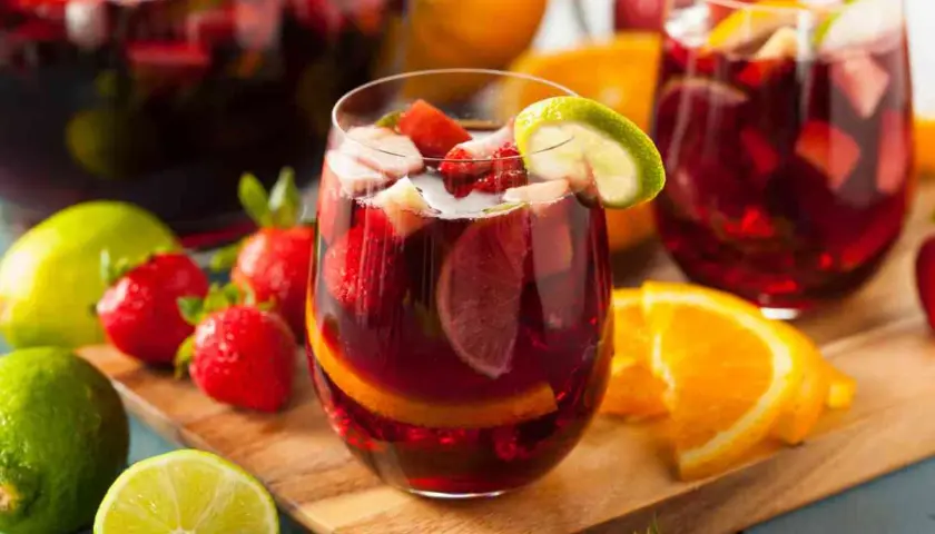 Sangria ricetta: bicchieri pieni di sangria con fragole, arance e lime. Frutta fresca intorno.