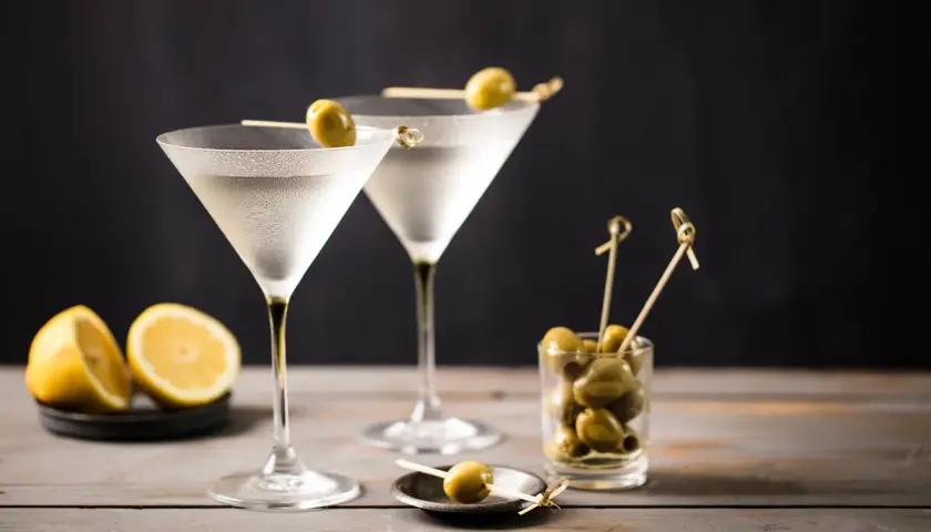 Due bicchieri di Martini, guarniti con olive, pronti per essere gustati. La martini ricetta IBA è un classico intramontabile.