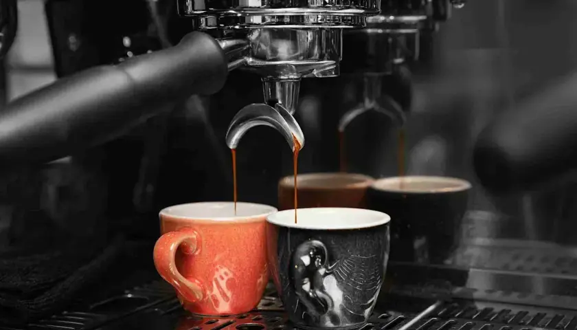 Caffè appena erogato in tazze colorate, un rituale quotidiano che richiede un decalcificante naturale per la macchina del caffè.