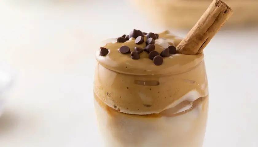 Un delizioso caffè freddo, con schiuma cremosa, gocce di cioccolato e un bastoncino di cannella.