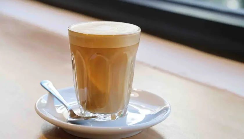 Un bicchiere di caffè latte con schiuma cremosa, pronto per essere gustato. Ecco come si fa un caffè latte perfetto.