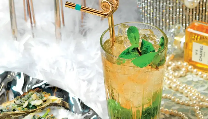 Un rinfrescante cocktail Italia, con menta e ghiaccio, accanto a ostriche gratinate e un flacone di profumo Chanel.