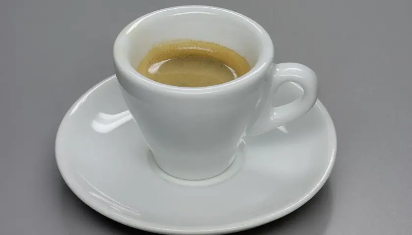 Tazza bianca con caffè espresso e crema, un omaggio a chi ha inventato il caffè espresso.