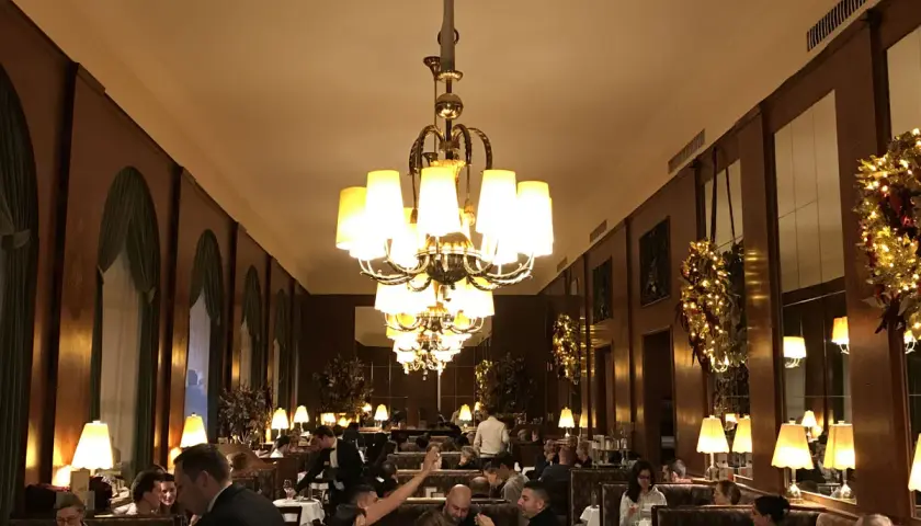 Interno elegante di uno dei caffè storici di Vienna, con tavoli apparecchiati, clienti e lampadari imponenti.