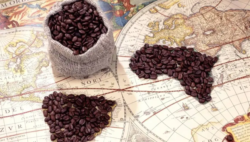 Chicchi di caffè su una mappa antica, che evocano il viaggio e la scoperta di chi ha inventato il caffè.