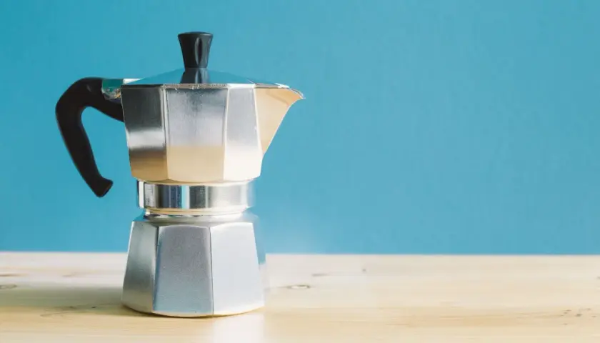 Moka italiana in alluminio, con manico nero, pronta per preparare un caffè. I suoi componenti sono ben visibili.