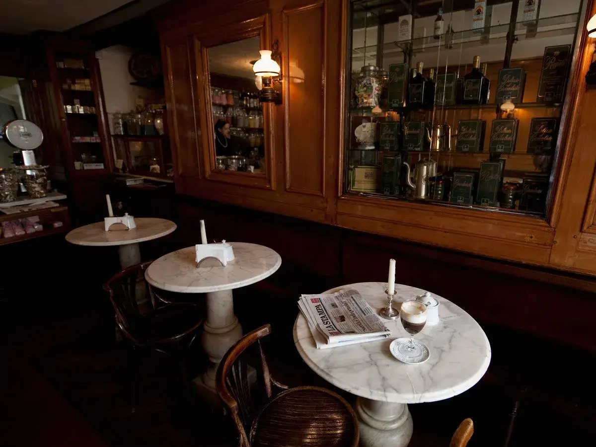 Un tavolino in marmo con un caffè, giornale e candela, in un antico caffè torinese.
