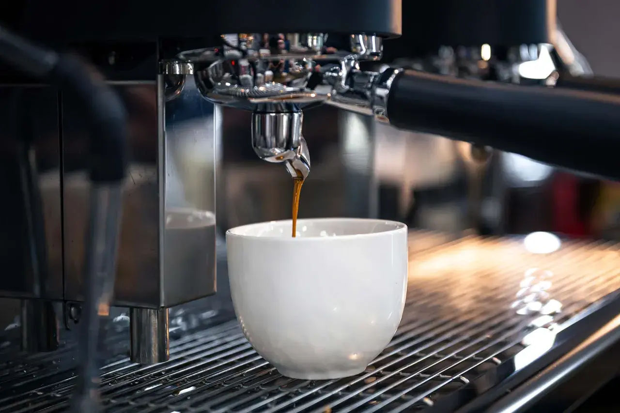 Un espresso scuro gocciola in una tazza bianca. Sorprendentemente, il caffè contiene glutine, un dettaglio che molti ignorano.
