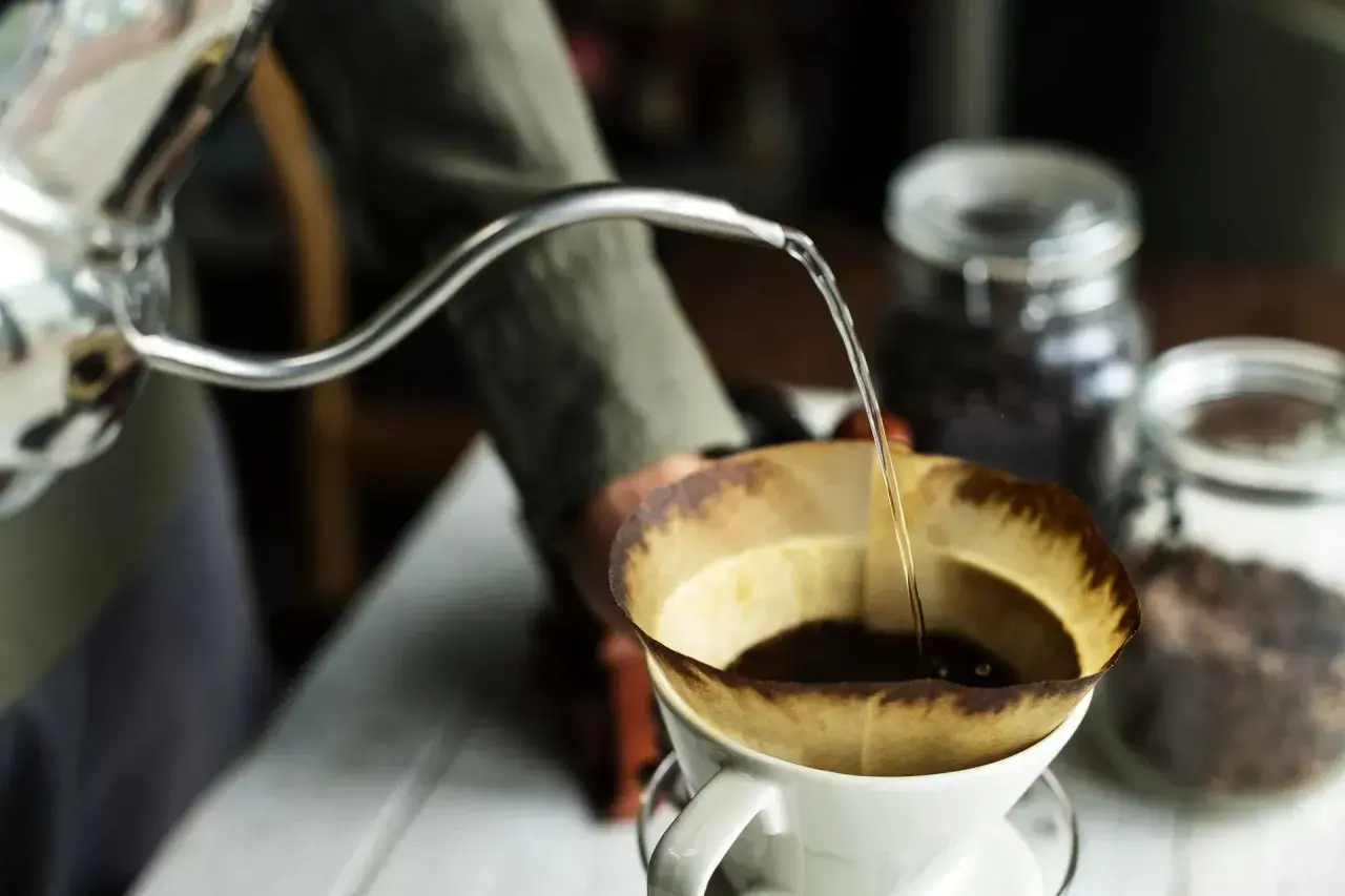 Preparazione di un v60 caffè: acqua calda versata lentamente su caffè macinato in un filtro di carta.