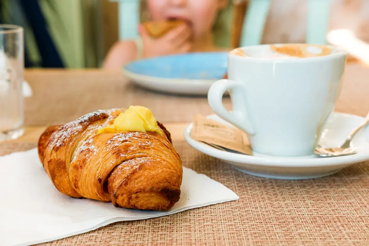 Un cornetto con crema e una tazza di cappuccino, un classico per la colazione italiana a casa.