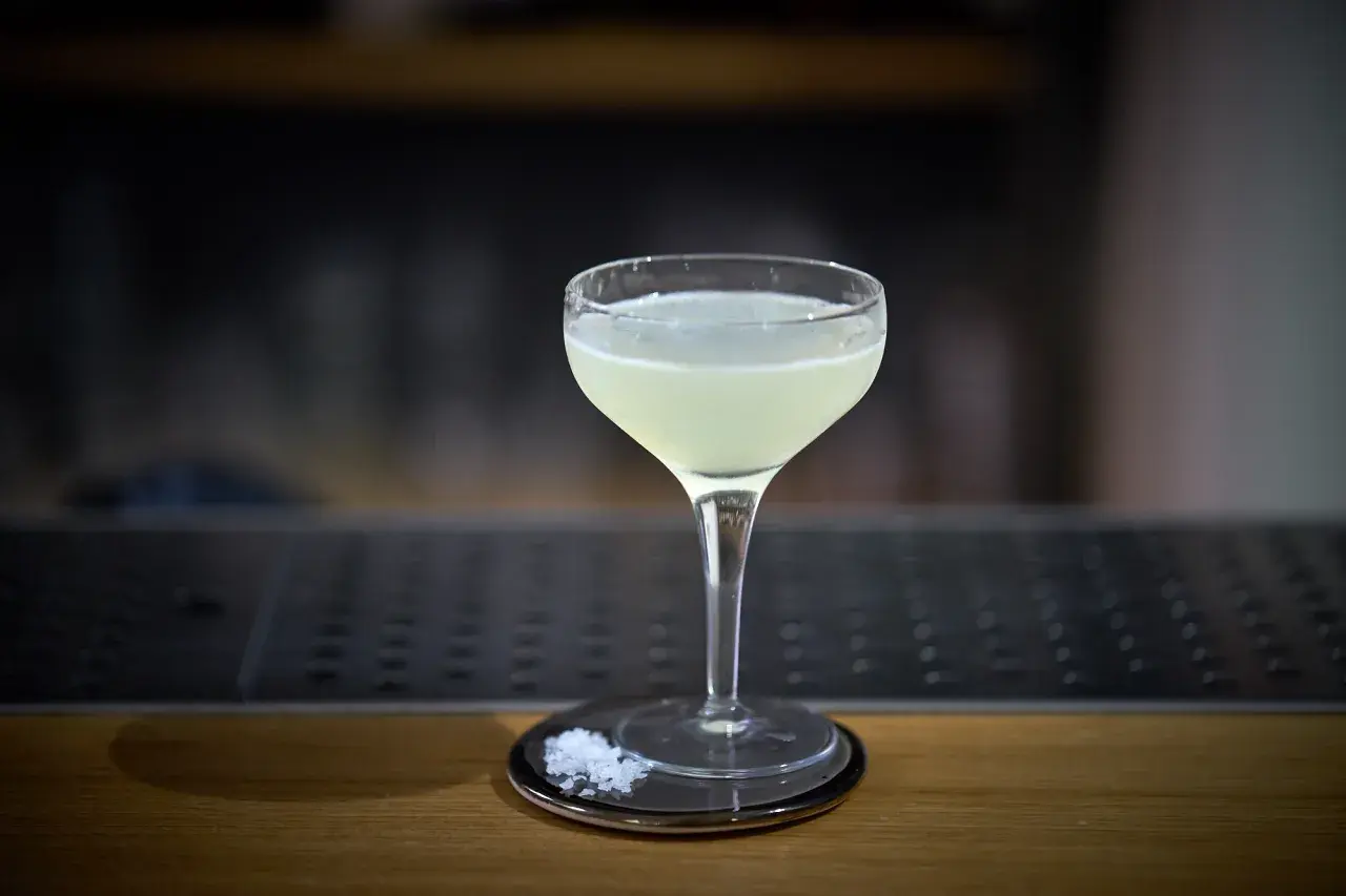 Un bicchiere di cocktail aspri, con sale grosso sul piattino, pronto per essere gustato.