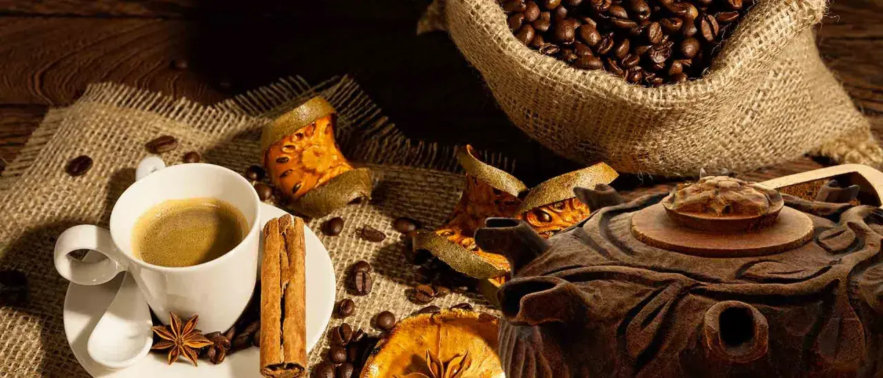 Tazza di caffè fumante, chicchi tostati, cannella e spezie. Una grolla ricetta per un momento di puro piacere.
