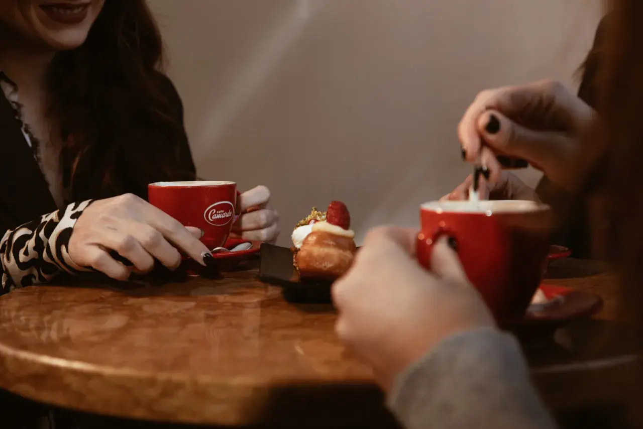 Due donne gustano un delizioso caffè e un dolce, condividendo un momento di relax.