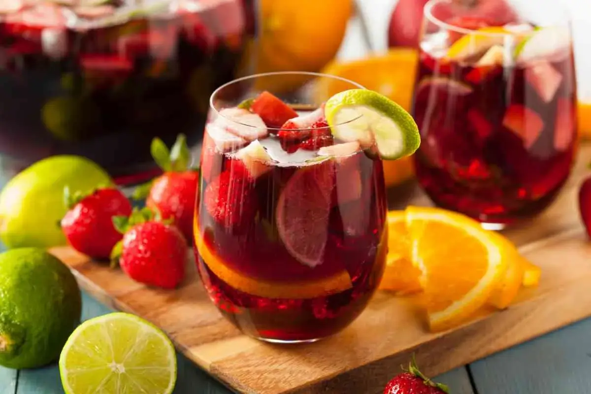 Sangria ricetta: bicchieri pieni di sangria con fragole, arance e lime. Frutta fresca intorno.