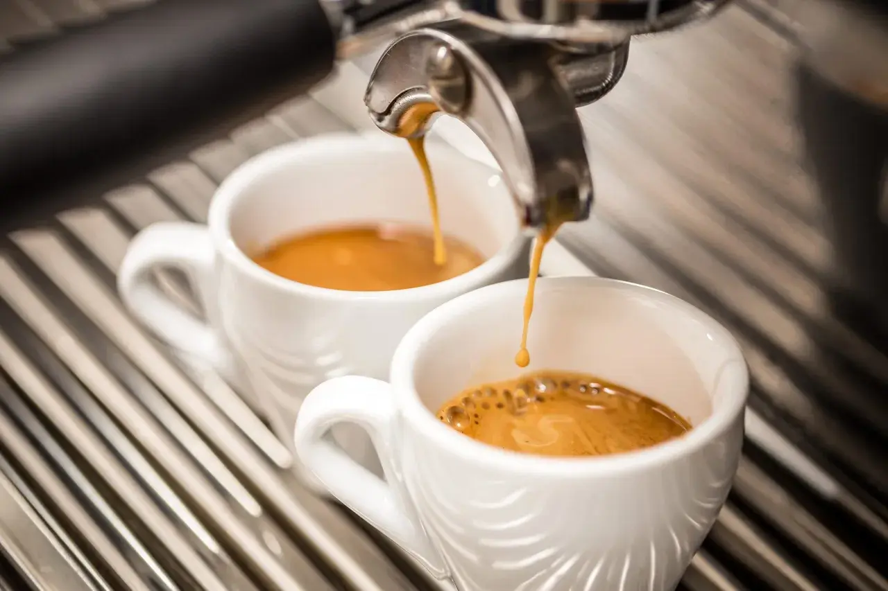 Due tazzine di caffè espresso vengono riempite da una macchina, ma il sapore bruciato del caffè rovina l'esperienza.
