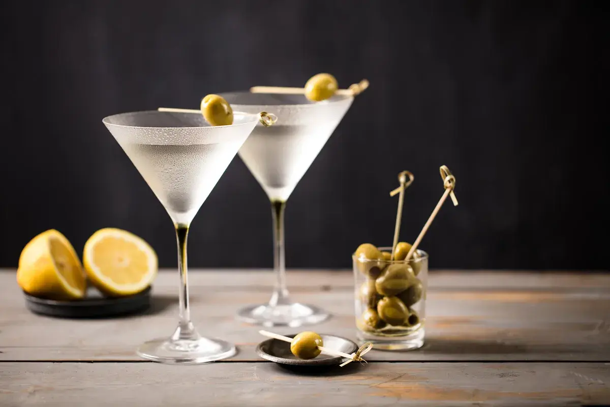 Due bicchieri di Martini, guarniti con olive, pronti per essere gustati. La martini ricetta IBA è un classico intramontabile.