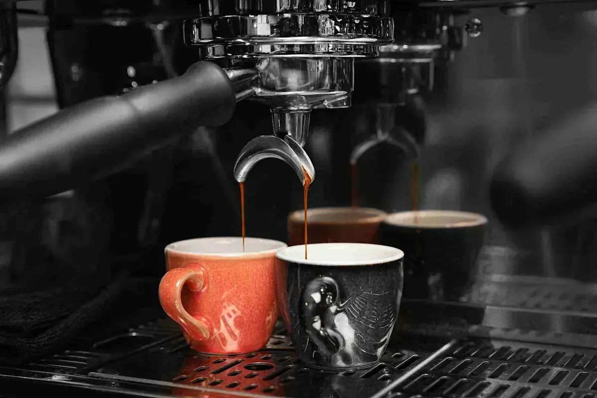 Caffè appena erogato in tazze colorate, un rituale quotidiano che richiede un decalcificante naturale per la macchina del caffè.