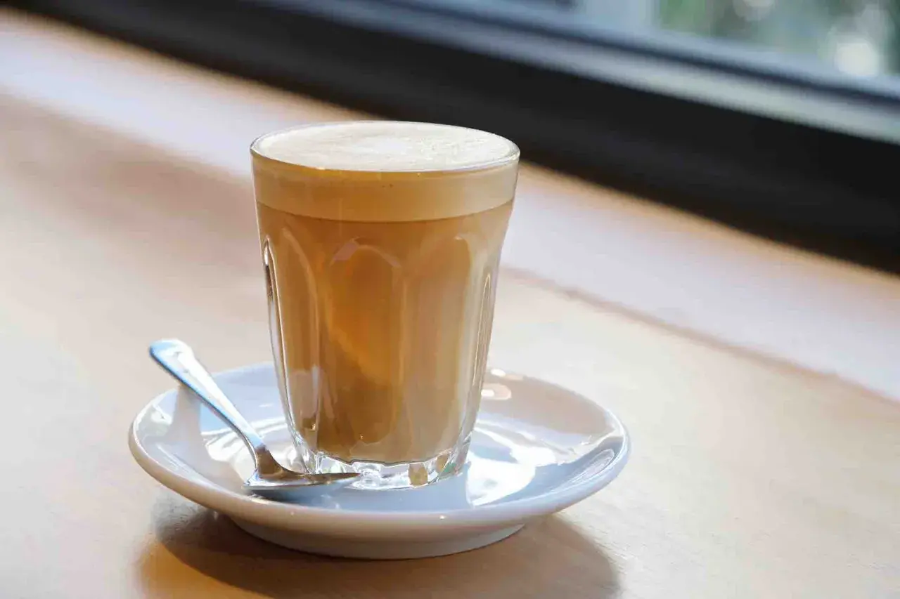 Un bicchiere di caffè latte con schiuma cremosa, pronto per essere gustato. Ecco come si fa un caffè latte perfetto.