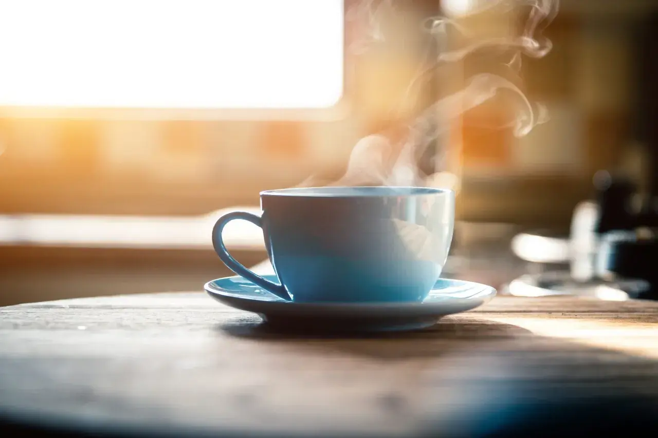 Tazza azzurra fumante su un tavolo di legno. Nonostante il suo aspetto invitante, il caffè è cancerogeno.