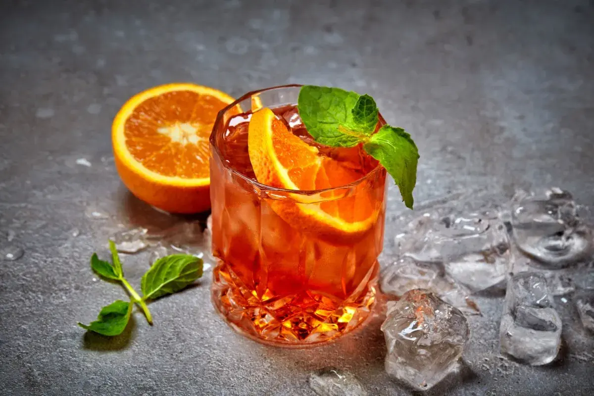 Rinfrescante cocktail con ghiaccio tritato, arancia e menta. Perfetto per un aperitivo estivo.