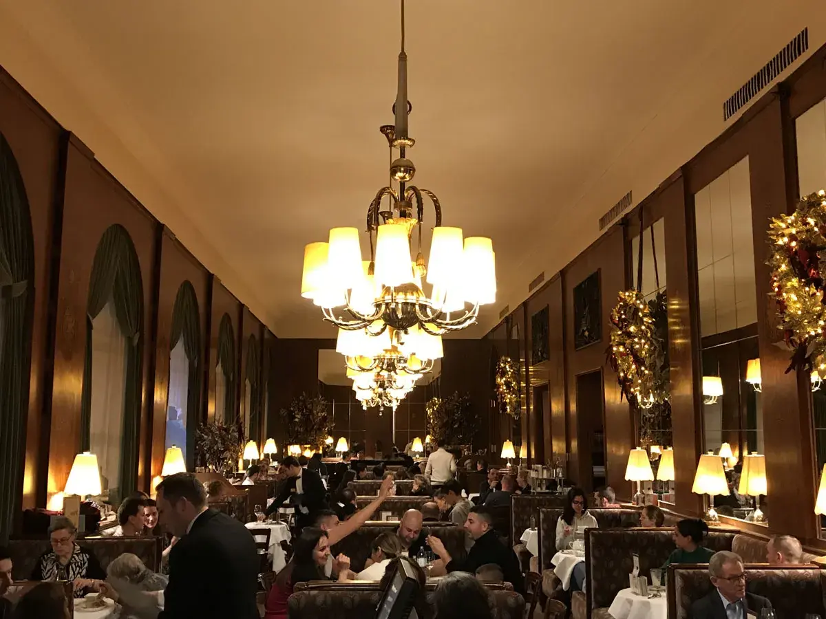 Interno elegante di uno dei caffè storici di Vienna, con tavoli apparecchiati, clienti e lampadari imponenti.
