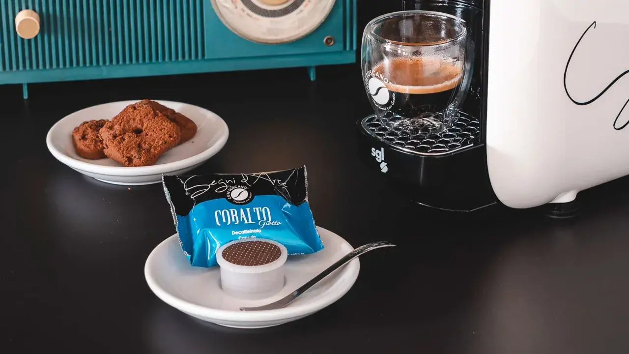 Un caffè decaffeinato pronto per essere gustato, accompagnato da biscotti al cioccolato e una macchina da caffè moderna.