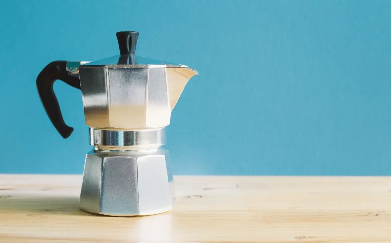 Moka italiana in alluminio, con manico nero, pronta per preparare un caffè. I suoi componenti sono ben visibili.