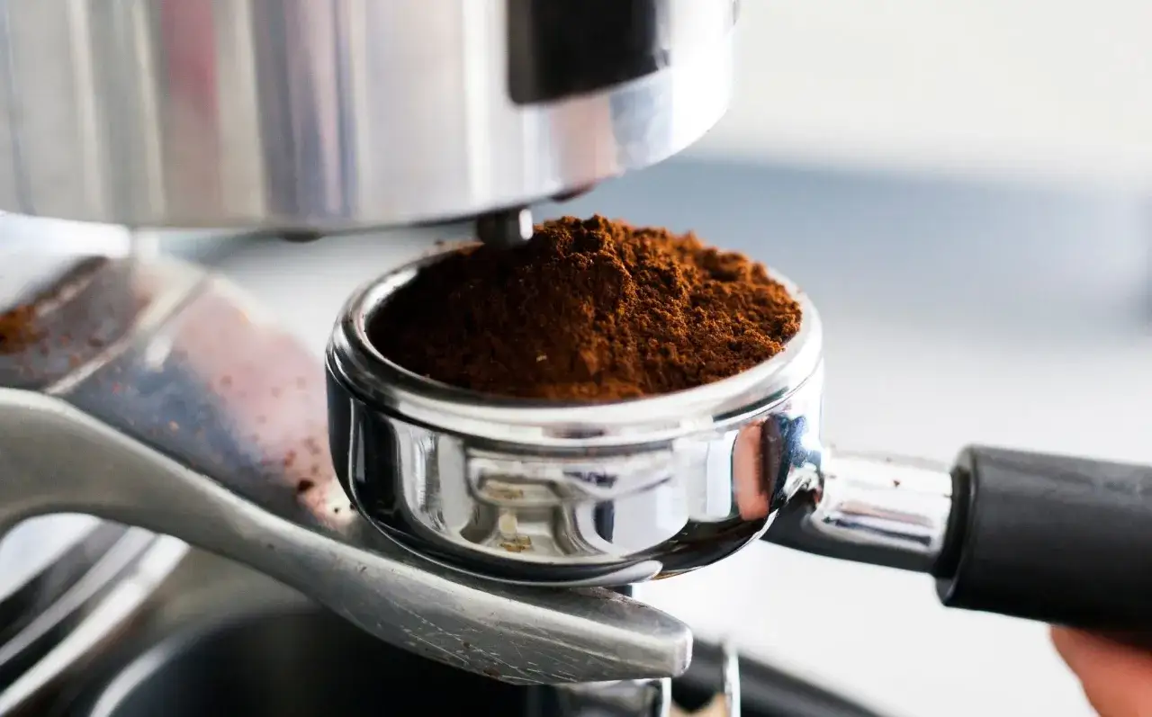 Macinatura caffè per moka, pronta per un espresso aromatico. Il caffè macinato riempie il portafiltro cromato.
