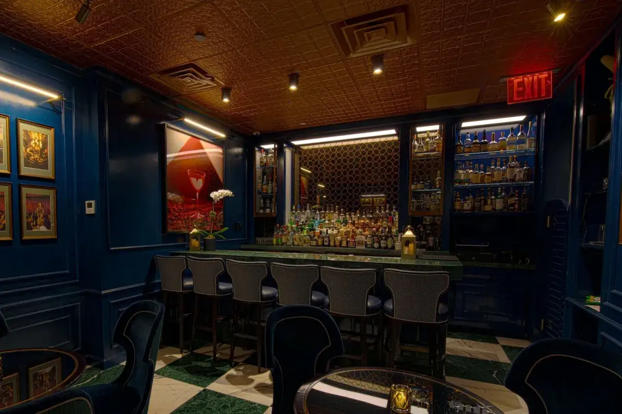 Un elegante bar blu con un soffitto dorato e un'ampia selezione di bottiglie. Un luogo perfetto per iniziare una cocktail storia.