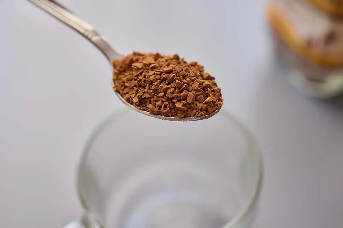 Un cucchiaino di caffè solubile pronto per essere sciolto in acqua calda. Ecco come si prepara un caffè veloce.