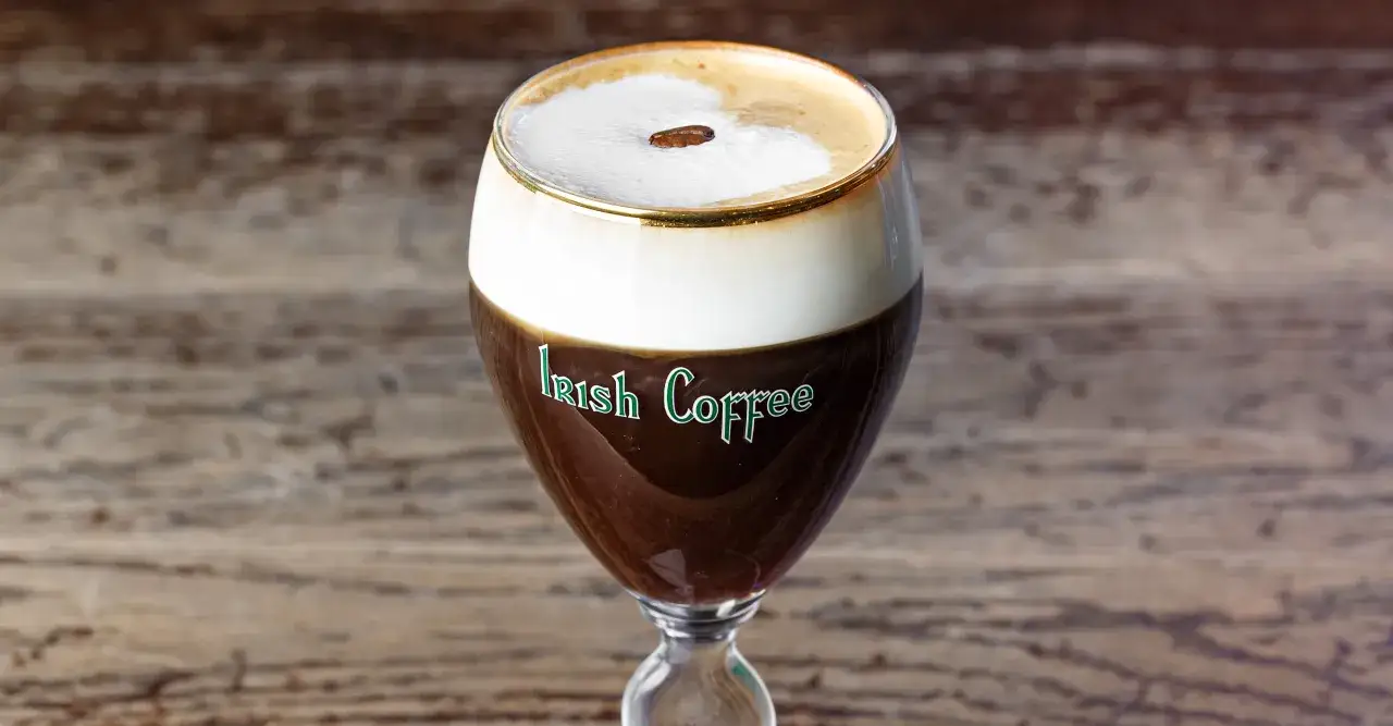 Un bicchiere di Irish Coffee con panna montata e un chicco di caff&egrave;. La ricetta perfetta per scaldarsi.