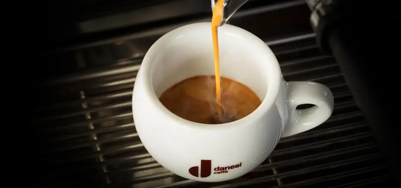Un espresso Danesi si versa in una tazza bianca, un momento di piacere per le donne e gli amanti del caffè.