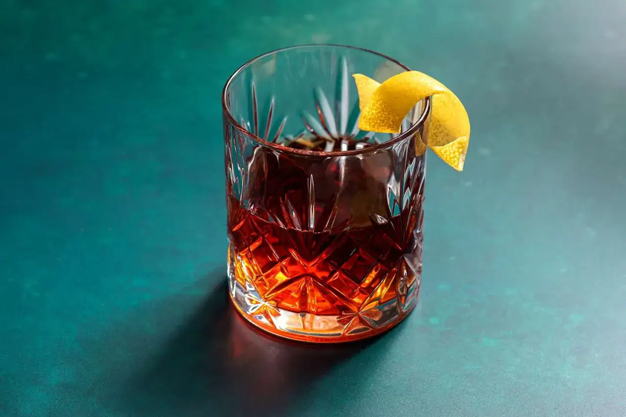 Sazerac, un classico IBA, servito in un bicchiere old fashioned con scorza di limone.