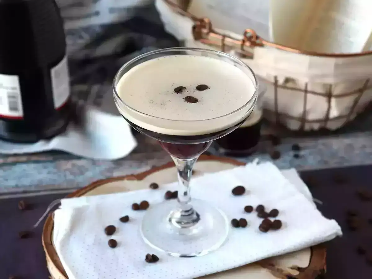Un delizioso cocktail espresso martini, con la sua schiuma cremosa e i chicchi di caffè a guarnire, pronto per essere gustato.