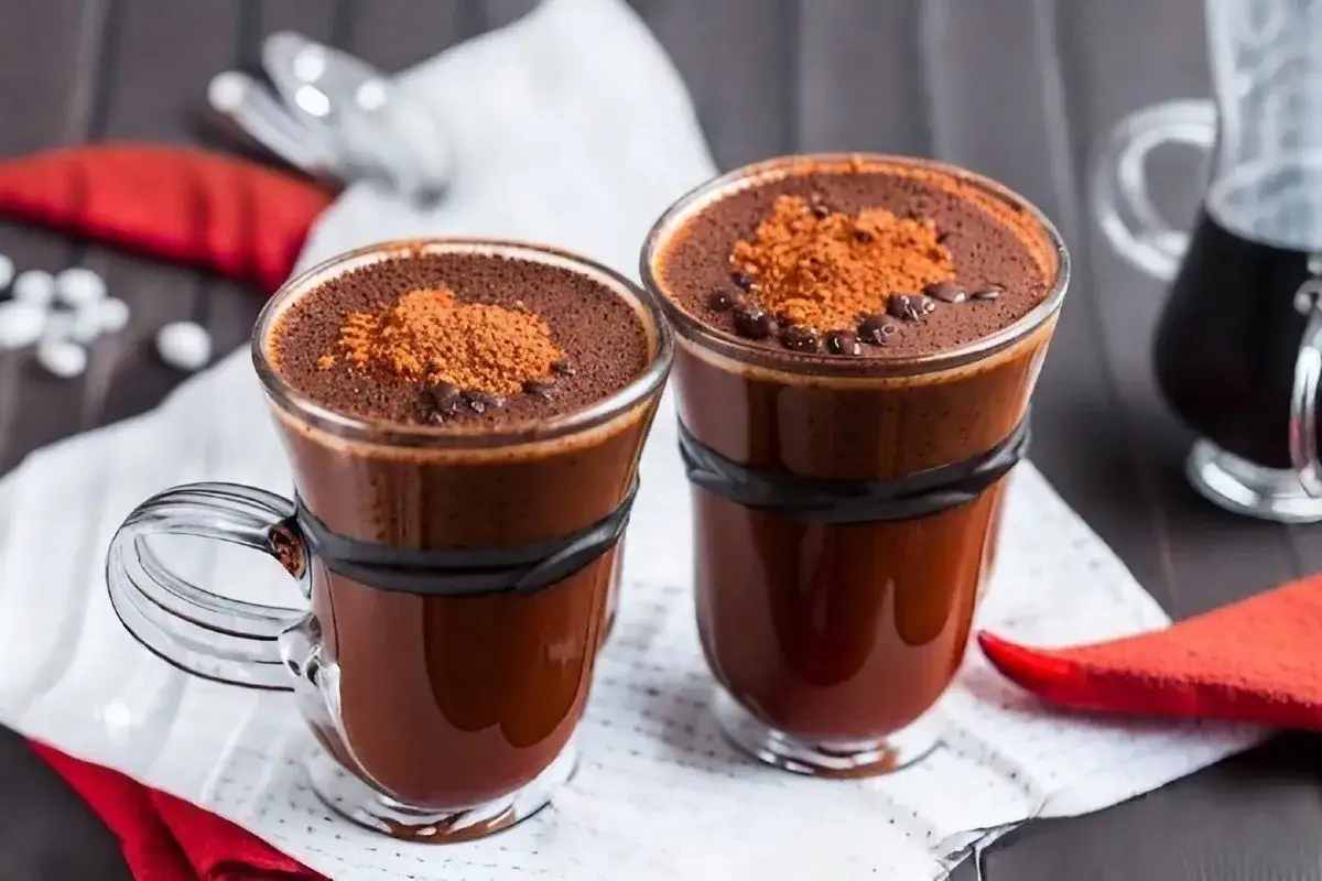 Due bicchieri di caff&egrave; con cioccolato, guarniti con cacao in polvere e gocce di cioccolato. Perfetti per una pausa golosa.