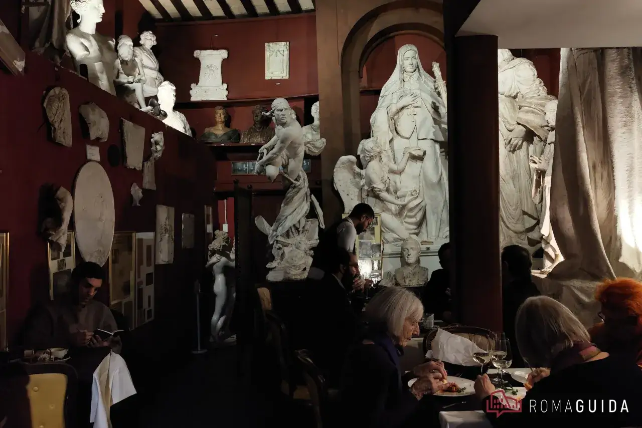 Un caff&egrave; a Roma famoso, tra sculture antiche e arte. Persone mangiano e leggono in un ambiente unico.