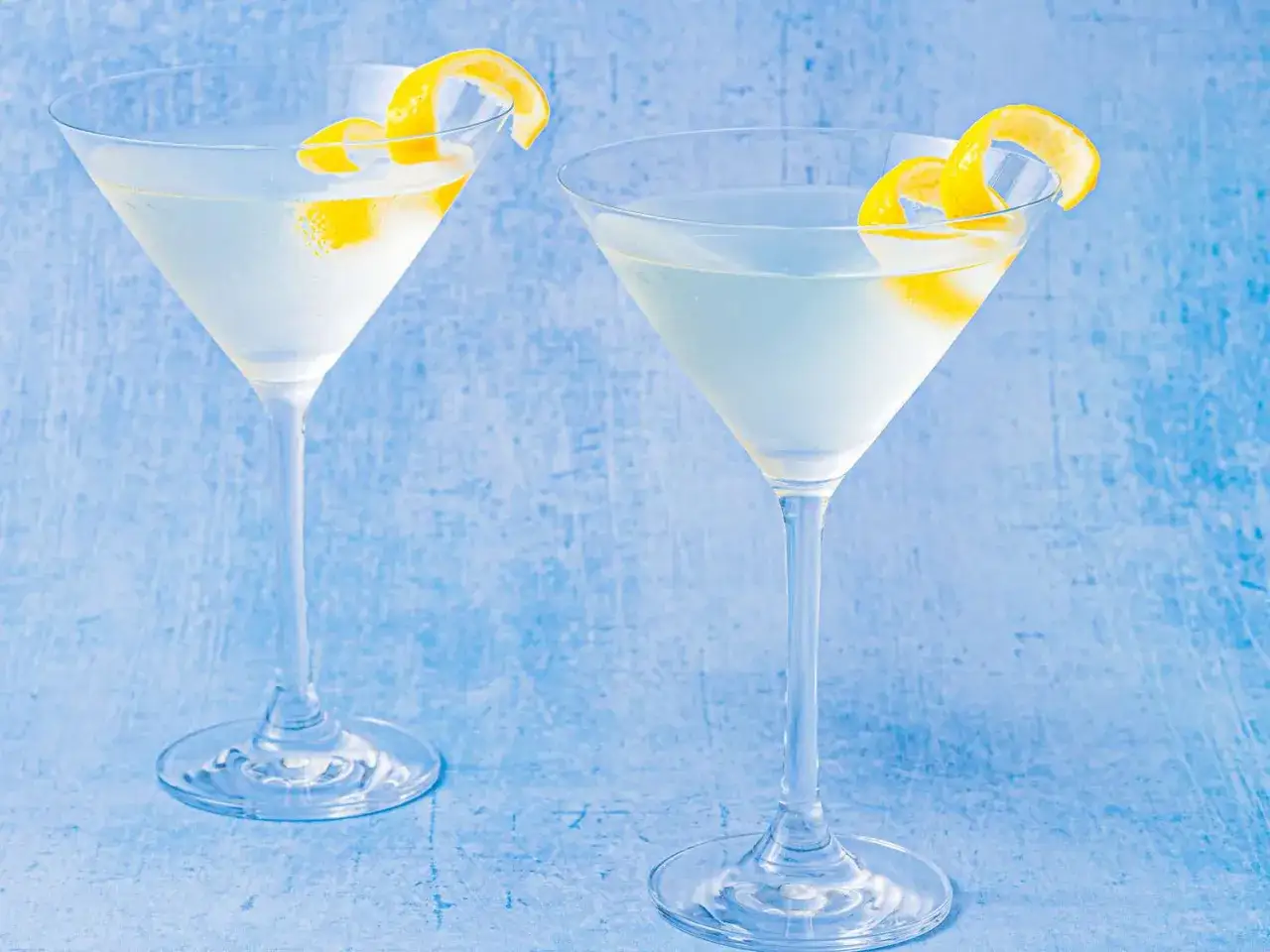 Due eleganti bicchieri da martini, guarniti con scorza di limone, pronti per gustare la classica martini ricetta iba.