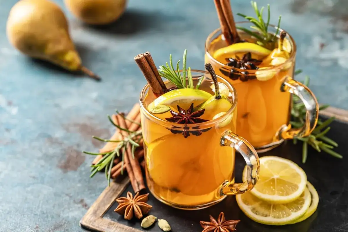 Due tazze di grog bevanda calda, guarnite con cannella, anice stellato, limone e rosmarino.