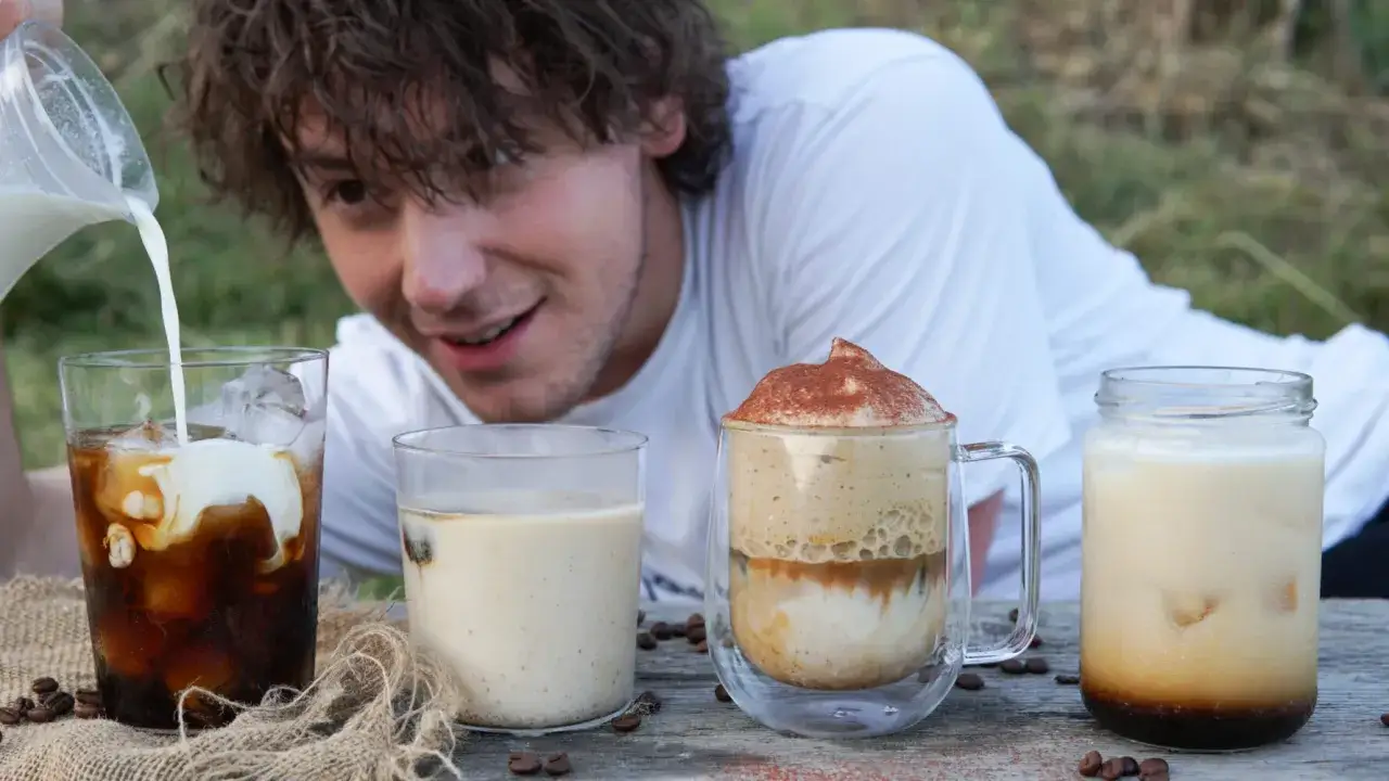 Un ragazzo versa latte in un bicchiere di caff&egrave; freddo. Sul tavolo ci sono altre bevande, tra cui un caff&egrave; schiumoso e un altro cold brew.