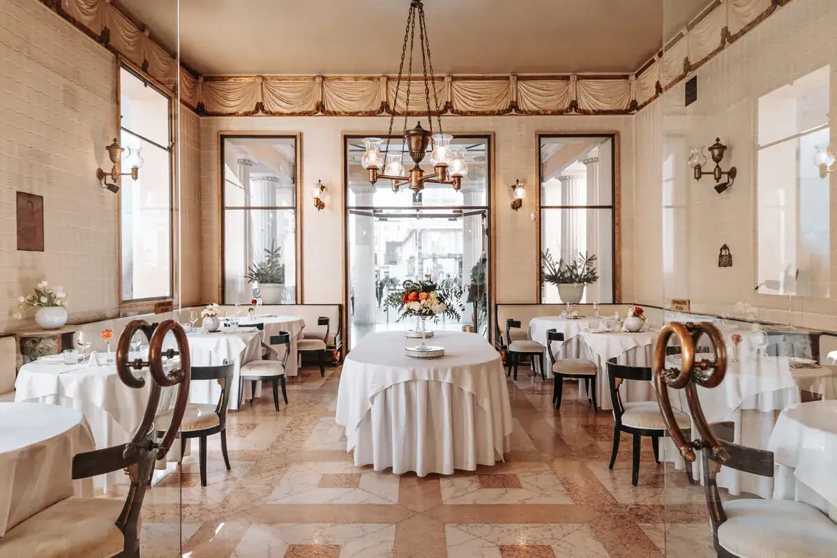 Interno elegante di un caffe storico a Padova, con tavoli apparecchiati e un grande bouquet al centro.